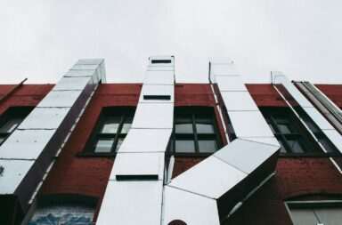 Low angle view of a modern industrial facade with prominent metal ducts on a red brick building.
