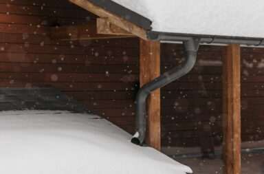 Snow-covered roofs with wooden structure during winter snowfall, capturing seasonal beauty.