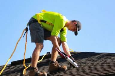 a man in a yellow shirt is working on a roof